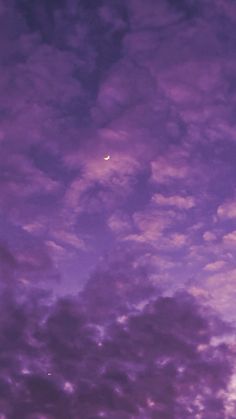 an airplane is flying in the sky at night with purple clouds and a bright moon