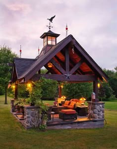 an outdoor living area with furniture and lights on the roof, surrounded by grass and trees