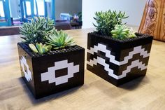 two planters made out of legos are sitting on a table with succulents in them