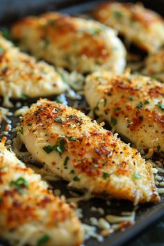 some chicken is cooking in a pan with parmesan cheese and herbs on top