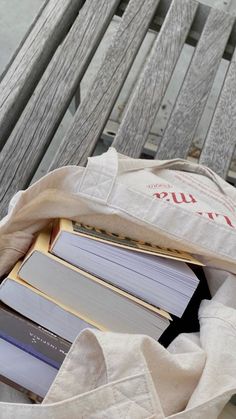 an open book bag sitting on top of a wooden bench next to a pile of books