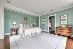 a bedroom with green walls and white furniture in the corner, along with hardwood flooring