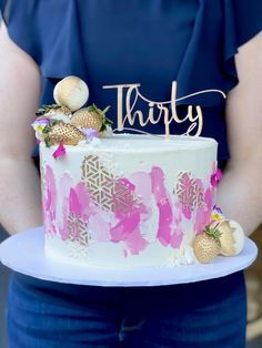 a woman holding a cake with the word thrift on it and strawberries in front