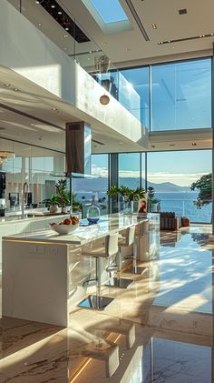 a large open floor plan living room and dining area with glass walls overlooking the ocean