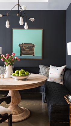 a dining room table with fruit on it in front of a blue wall and black couch