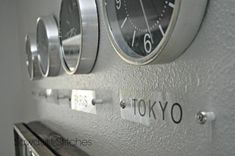 three clocks mounted to the side of a wall with tokyo written on it and below them