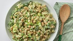 a white bowl filled with macaroni salad next to a green napkin and wooden spoon