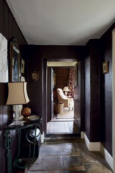 a hallway with dark wood paneling and white trim on the walls, along with two lamps