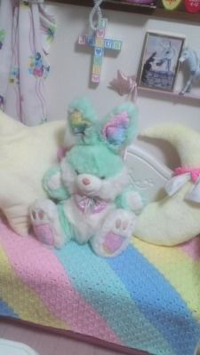 a stuffed animal sitting on top of a bed next to a baby crochet blanket