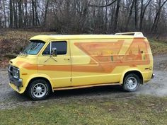 a yellow van parked on top of a gravel road in front of trees and grass