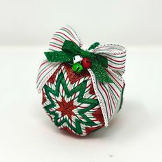 an ornament is decorated with green and red ribbons