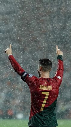 a soccer player in the rain with his arms up