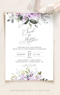 an elegant wedding card with purple flowers and greenery