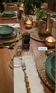 a wooden table topped with green plates and silverware next to candlelight candles in wicker baskets