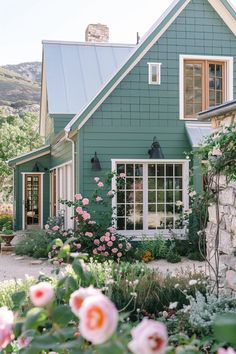 a green house with pink flowers in the front yard