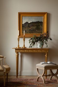 a painting on the wall next to a small table with a candle and a chair