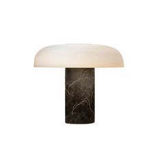 a black and white table lamp with a marble base on an isolated white wall background