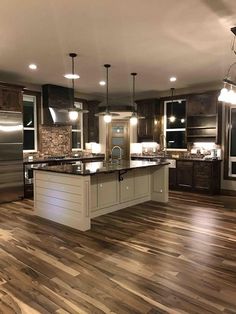 a large kitchen with wooden floors and stainless steel appliances