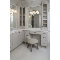 a large bathroom with white cabinets and marble counter tops, along with two stools