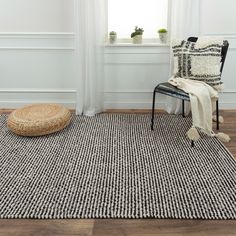 a black and white area rug in front of a window with a wicker basket on the floor