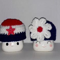 two white ceramic pots with red, white and blue crocheted hats on them