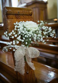 a bouquet of white flowers sitting on top of a wooden bench in front of a pew