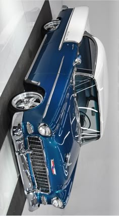 an old blue car is parked in a room with black and white stripes on the floor