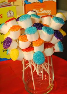 a glass vase filled with colorful marshmallows on top of a red table