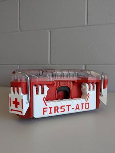 a red and white first aid kit sitting on top of a table next to a brick wall