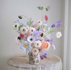 a vase filled with lots of colorful flowers on top of a table next to a window