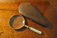 a magnifying glass sitting on top of a wooden table next to a piece of wood