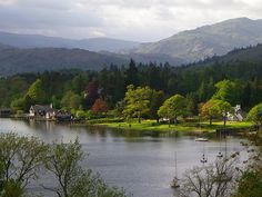 a body of water surrounded by trees and mountains in the distance with houses on it