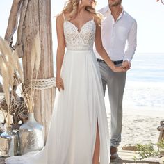 a man and woman standing next to each other in front of a wooden structure on the beach