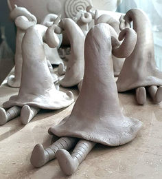 some white clay figures sitting on top of a table next to each other in front of a mirror