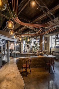 an industrial style bar with lots of lights hanging from the ceiling and chairs around it