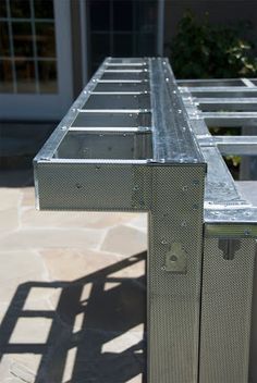 a metal table sitting on top of a stone floor next to a building with windows