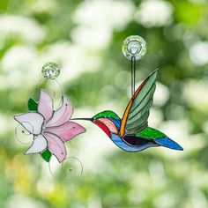 a stained glass hummingbird and flower hanging from a window