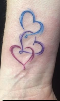 a tattoo on the wrist of a woman with a heart and two hands holding each other