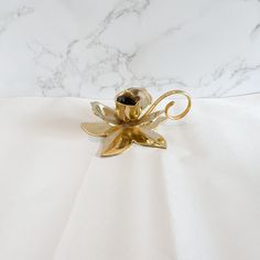 a gold candle holder sitting on top of a white tablecloth covered floor next to a marble wall