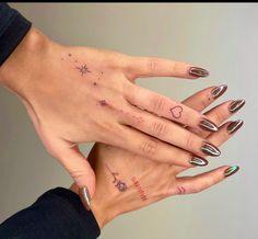 two women's hands with tattoos on their fingers and one holding the other hand