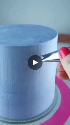 a woman is using a pair of scissors to cut the top of a blue cake