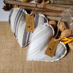 two heart shaped pillows with tags on them sitting next to some sticks and other items