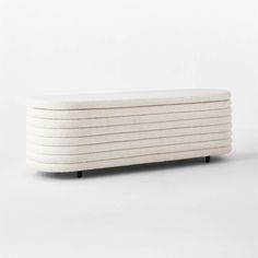 an upholstered bench made out of white wool with black legs and wooden feet