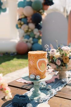 a table topped with a cake covered in frosting next to a vase filled with flowers