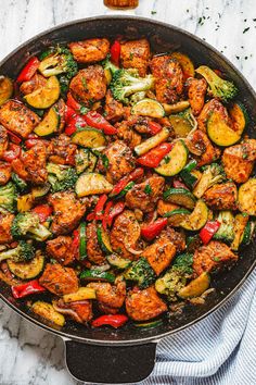 a skillet filled with chicken and veggies on top of a marble counter