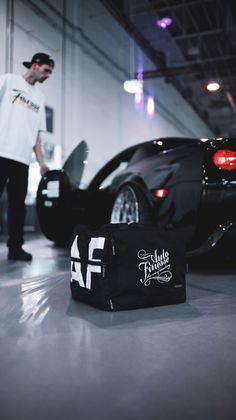 a man standing next to a black sports car