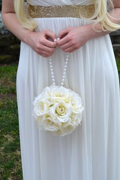 a woman in a white dress holding a flower and beaded brooch on her belt