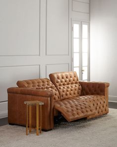 a brown leather couch sitting on top of a carpeted floor next to a table