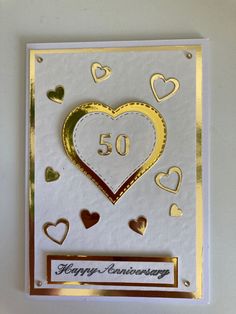 a 50th anniversary card with gold foil hearts and the number 50 on it's front