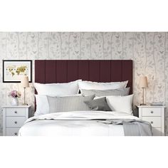 a bed with white sheets and pillows in a bedroom next to a wallpapered wall